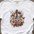 White Christian graphic t-shirt featuring a floral cross design with the word “Faith” centered across the cross.