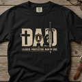 Christian graphic t-shirt featuring the word “Dad” with faith-inspired symbols including a cross, shield, sword, praying figure, and the phrase “Leader. Protector. Man of God.” with Ephesians 6:4.