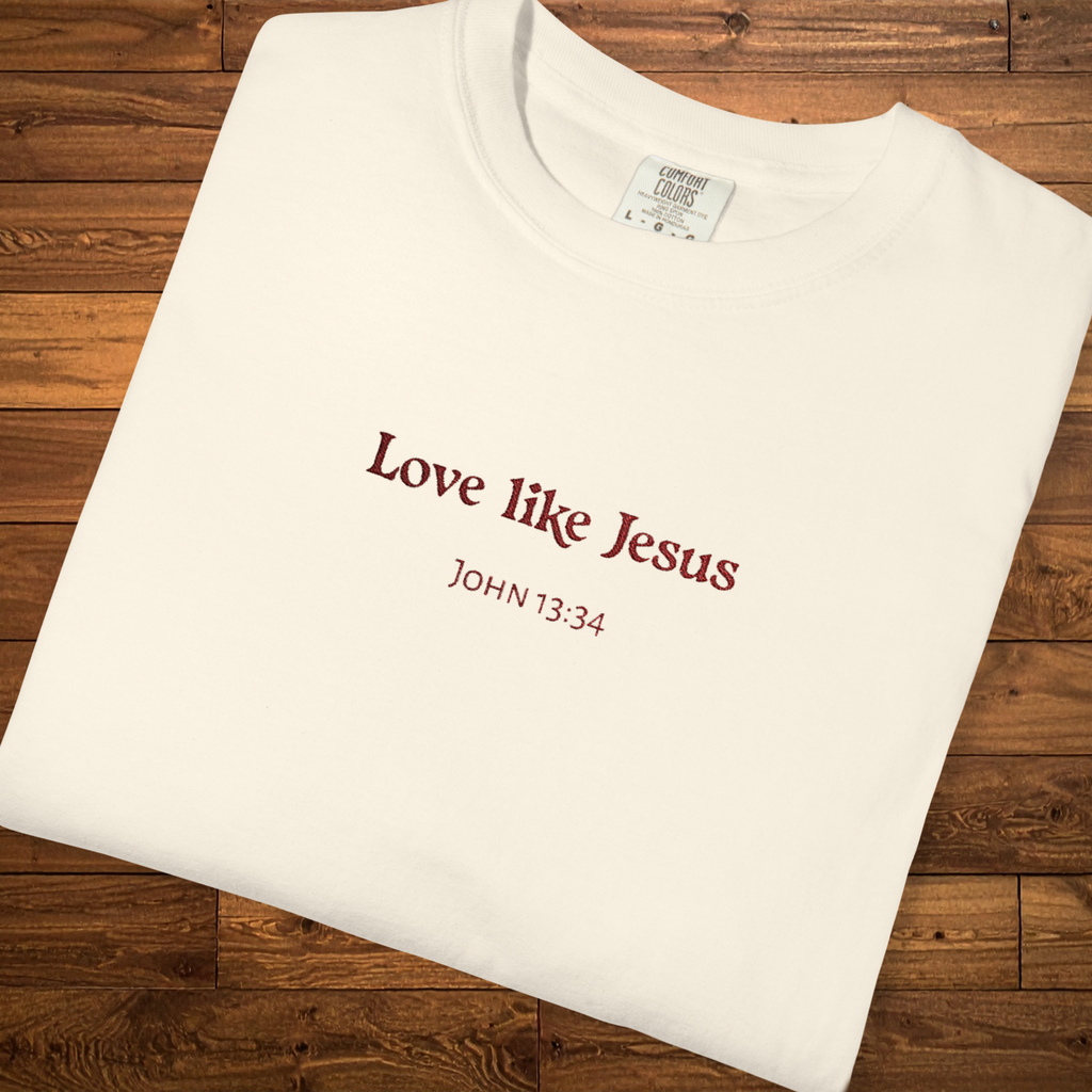 Faith-based garment-dyed t-shirt in ivory featuring the embroidered-style message “Love Like Jesus” with John 13:34 centered on the chest.