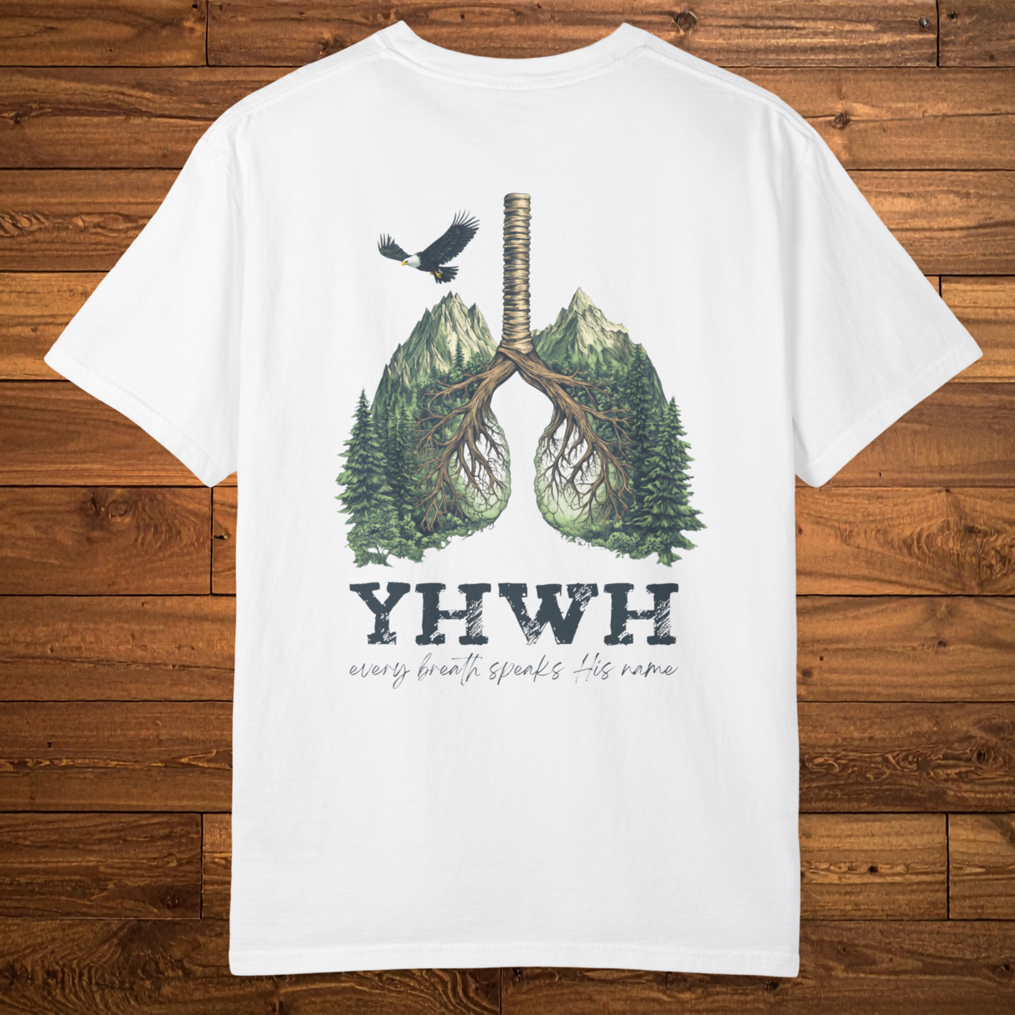 Back of a white faith-based t-shirt featuring lungs formed from mountains, trees, and roots above the phrase “YHWH – every breath speaks His name.”