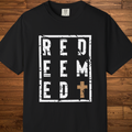 A black short-sleeve t-shirt with a distressed white graphic reading 'RED EEM ED' and a brown cross, displayed flat against a rustic wooden plank background.